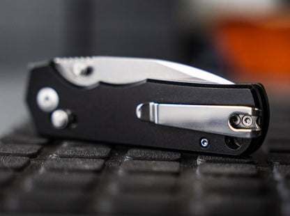 Close-up of a folding knife on a textured surface with a blurred background