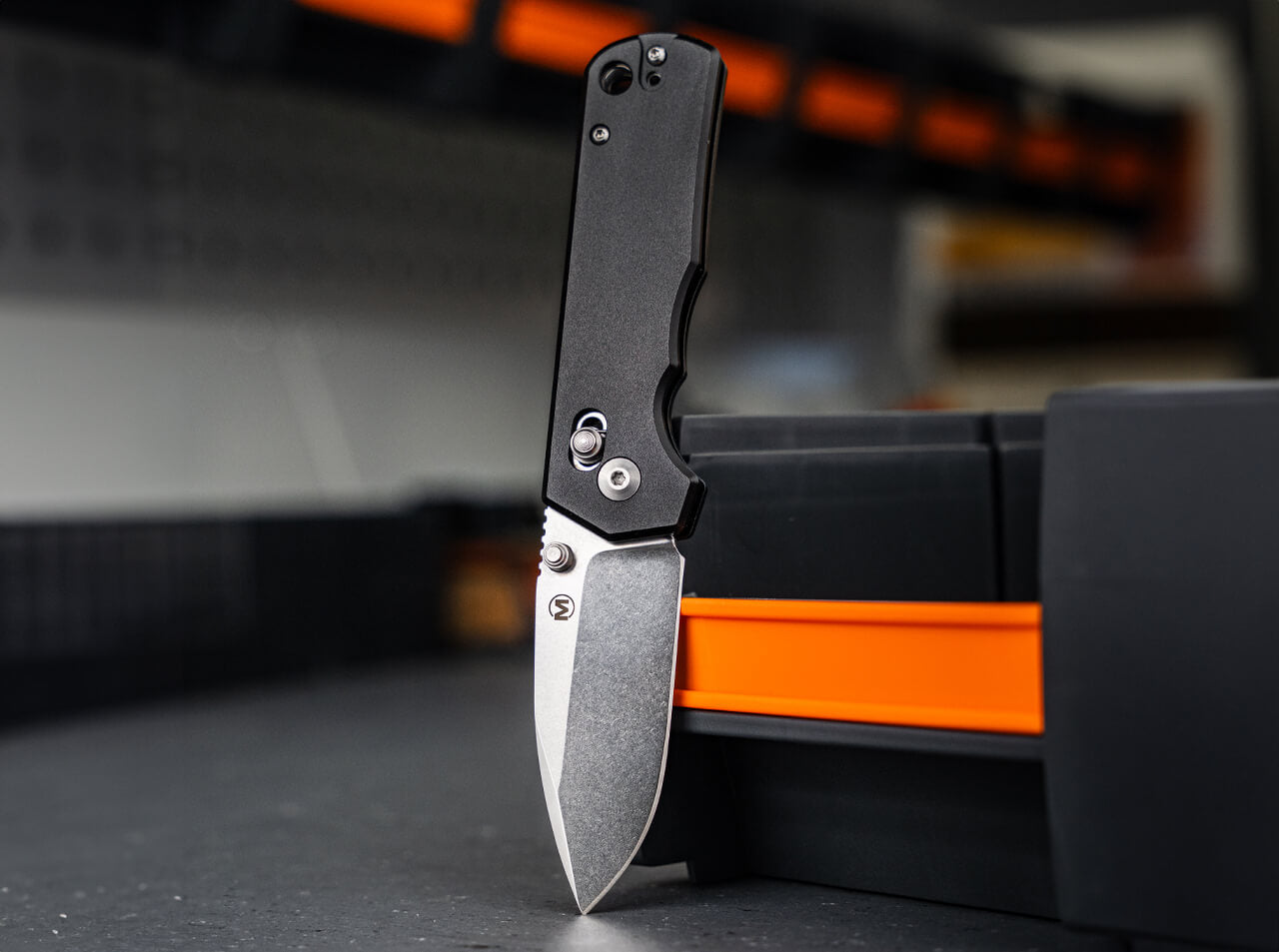 Folding knife with black handle and silver blade on a blurred background