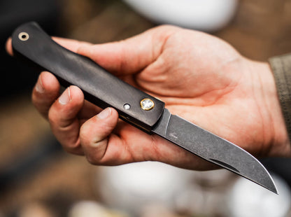 Hand holding a folding knife with a blurred background