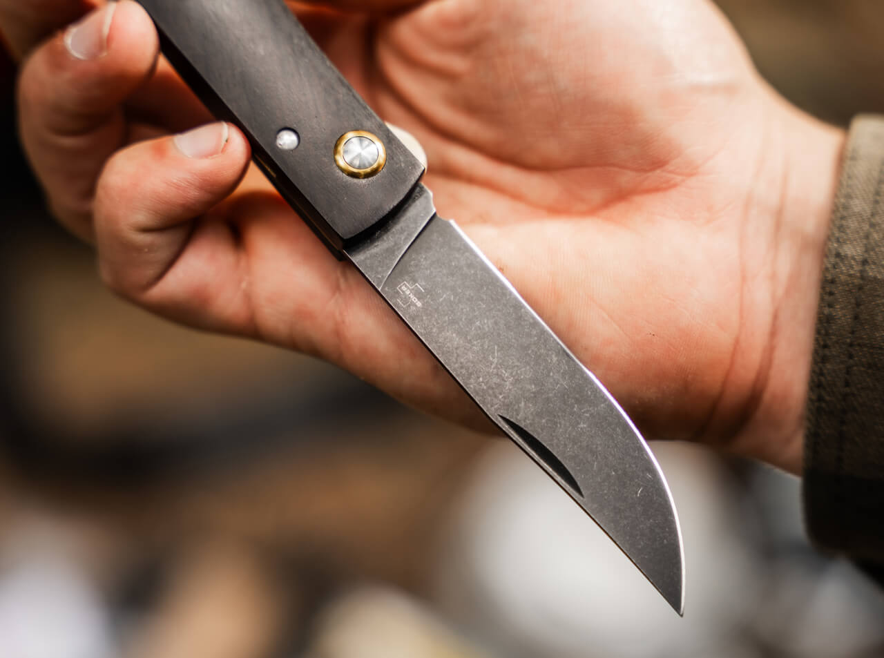 Hand holding a folding knife with a blurred background
