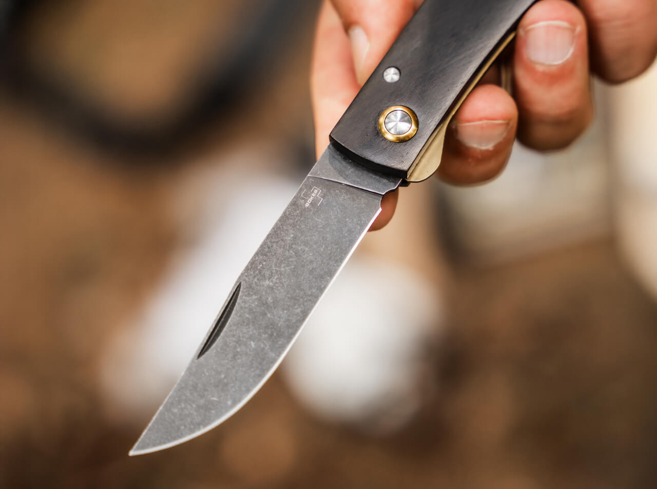 Hand holding a folding knife with a blurred background