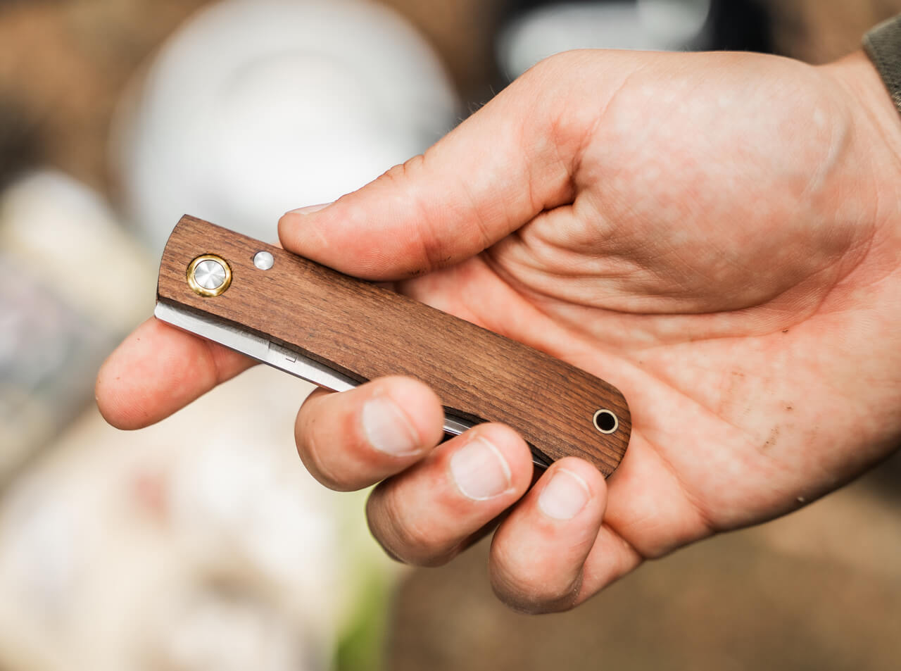 Hand holding a wooden folding knife with a blurred background