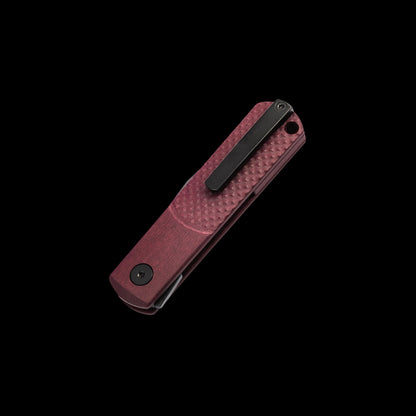 A pocket knife with a textured reddish-brown handle and a black clip, shown diagonally on a solid black background.