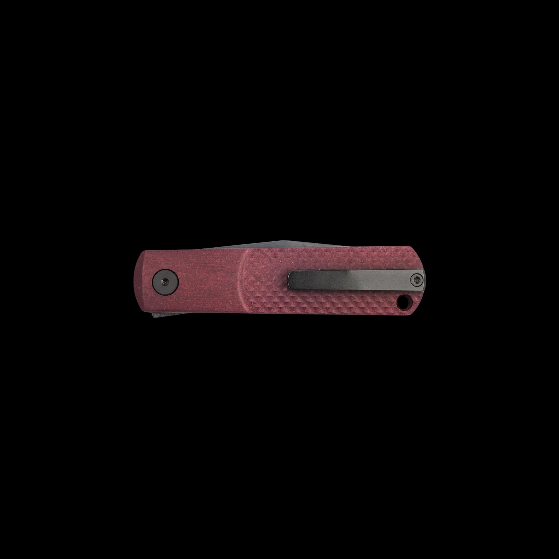 A folding pocket knife with a textured reddish-pink handle and a dark gray metal clip, shown horizontally against a solid black background.