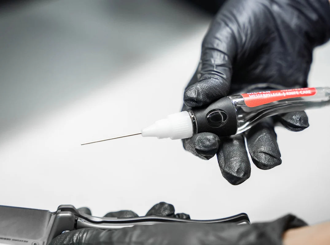 Person wearing black gloves using a tool on a metallic surface