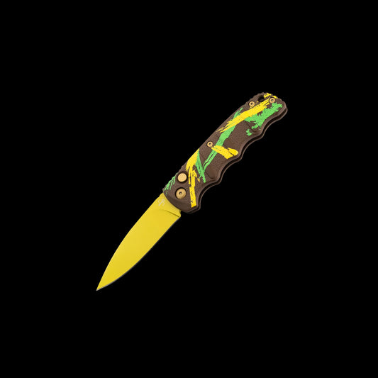 A folding pocket knife with a yellow blade and a dark brown handle featuring green and yellow splatter-style graphics, shown against a solid black background.