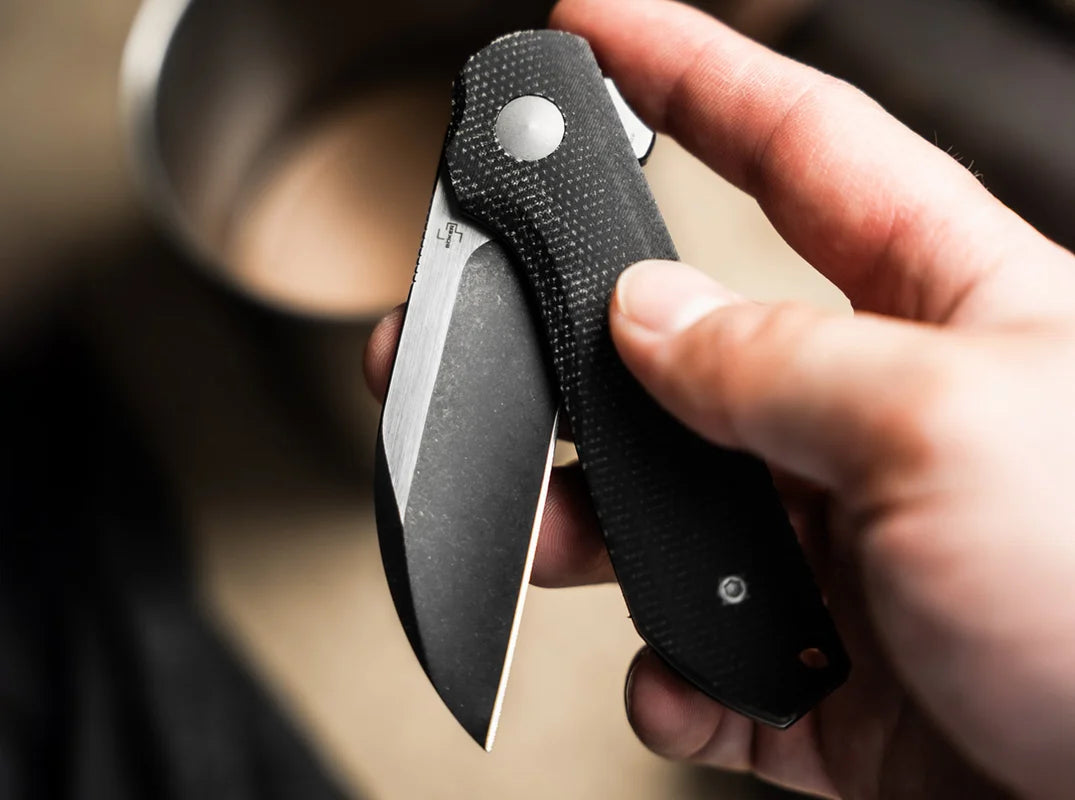 Hand holding a folding knife with a blurred background