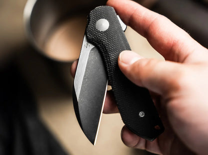 Hand holding a folding knife with a blurred background