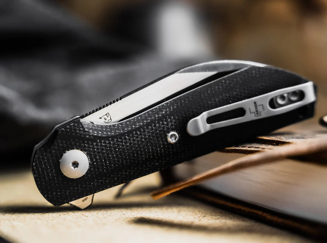 Black folding knife with silver blade on a wooden surface
