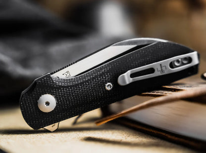 Black folding knife with silver blade on a wooden surface