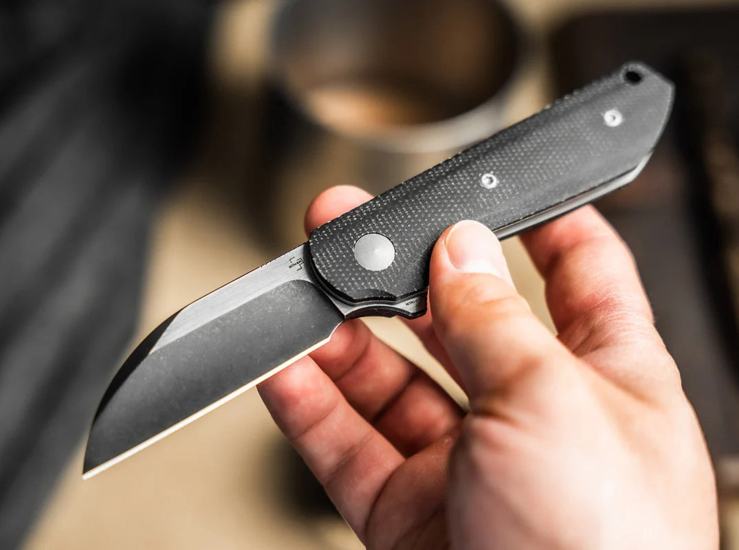 Hand holding a folding knife with a blurred background