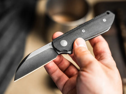 Hand holding a folding knife with a blurred background
