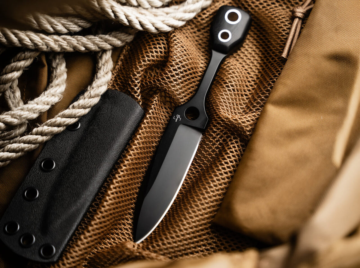Black folding knife with sheath on a textured surface