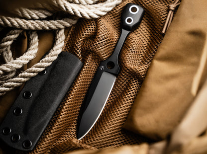 Black folding knife with sheath on a textured surface