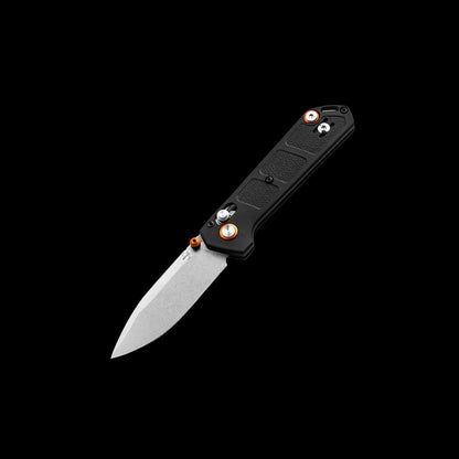 A folding pocket knife with a black textured handle and a satin-finished silver blade, shown open against a solid black background. The handle features orange accents around the pivot screw and a silver pocket clip.