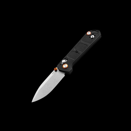 A folding pocket knife with a black textured handle and a satin-finished silver blade, shown open against a solid black background. The handle features orange accents around the pivot screw and a silver pocket clip.